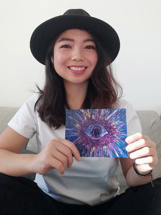 Photo of Jo Bautista, founder of SendToGive, holding one of her postcard art pieces