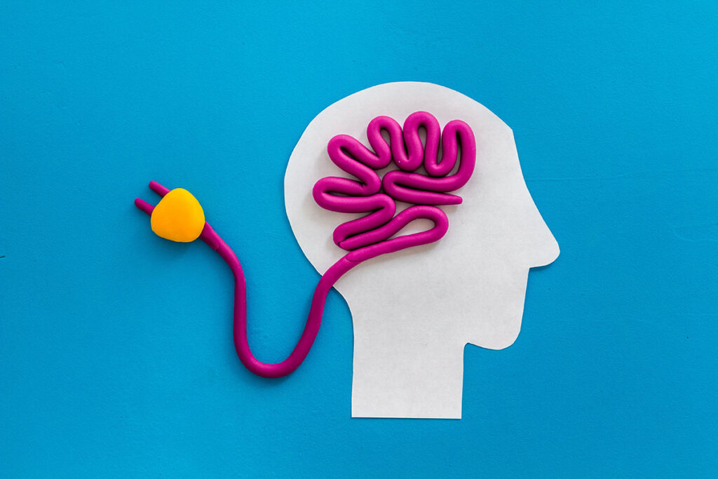 Brain charging and mental rest. Plug and cable leads to plastiline meanders on blue background top view, ©9dreamstudio / AdobeStock