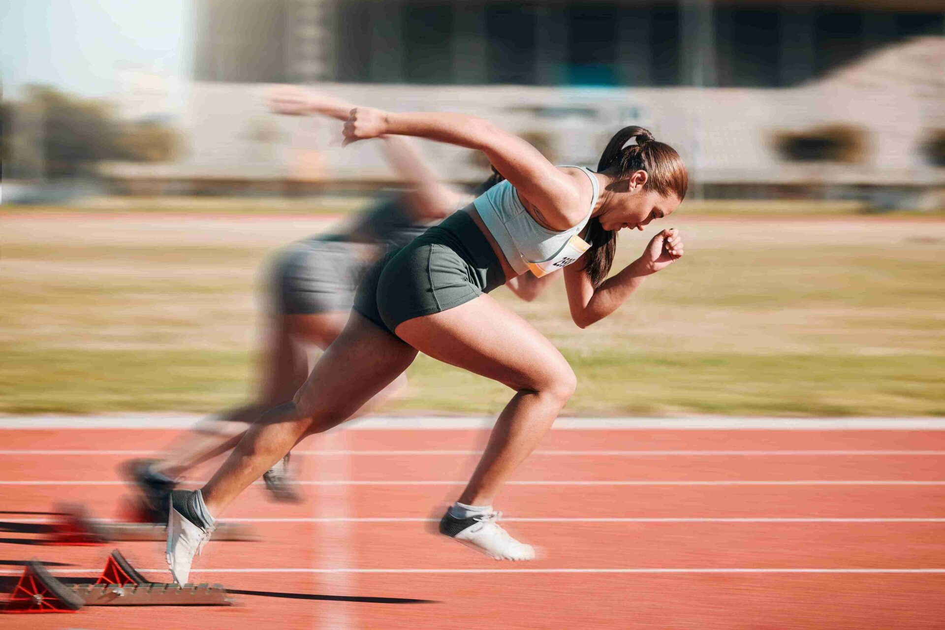 A woman running on a track going fast enough that her legs are blurry.