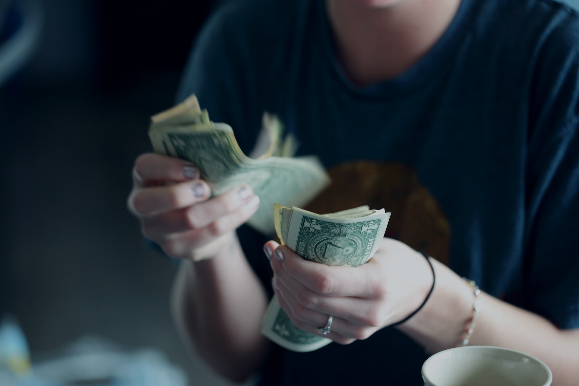 Photo of a woman counting dollar bills.