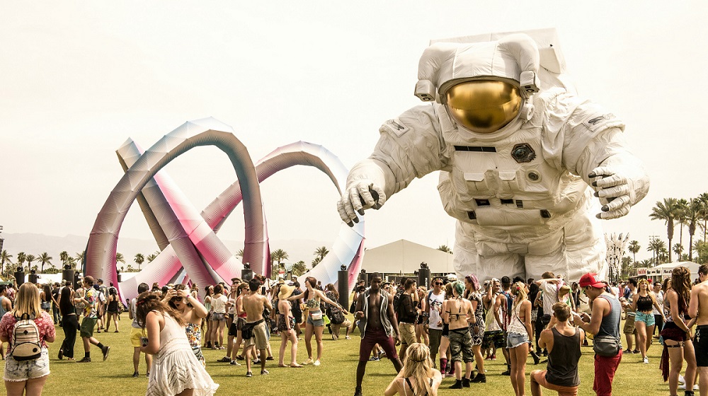 Picture from Coachella. A large blow-up astronaut stands over a crowd dressed in festival clothing.