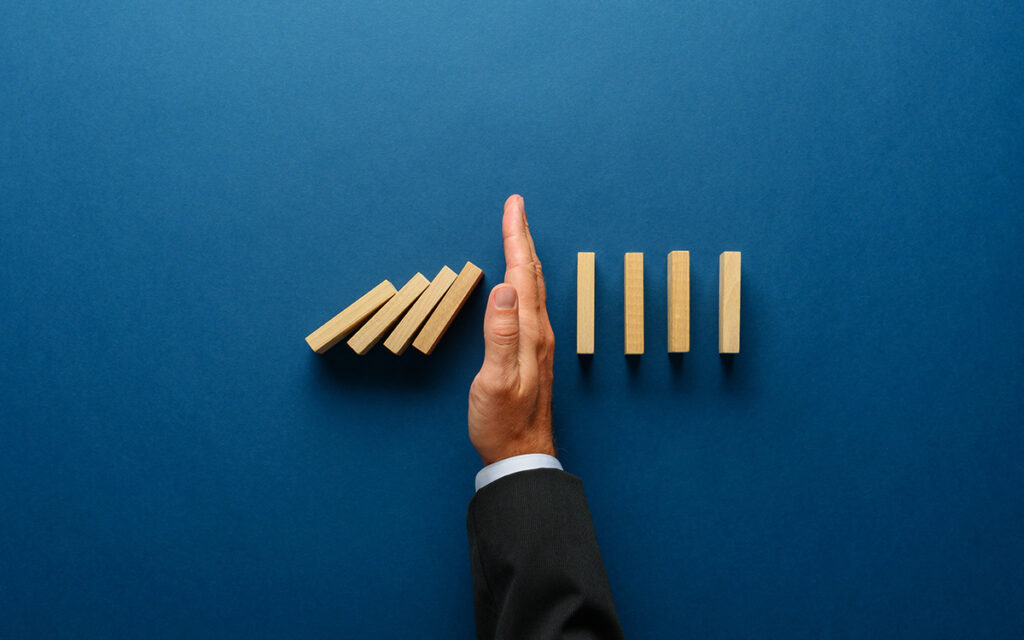 Photo of a hand blocking falling dominos