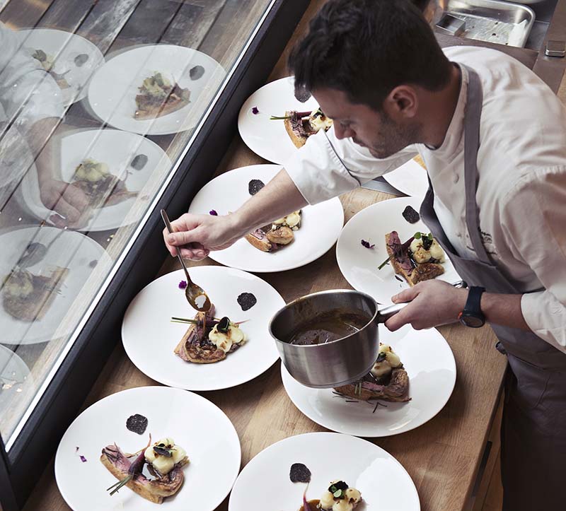 Professional chef plating dishes in a guest's home. © La Belle Assiette