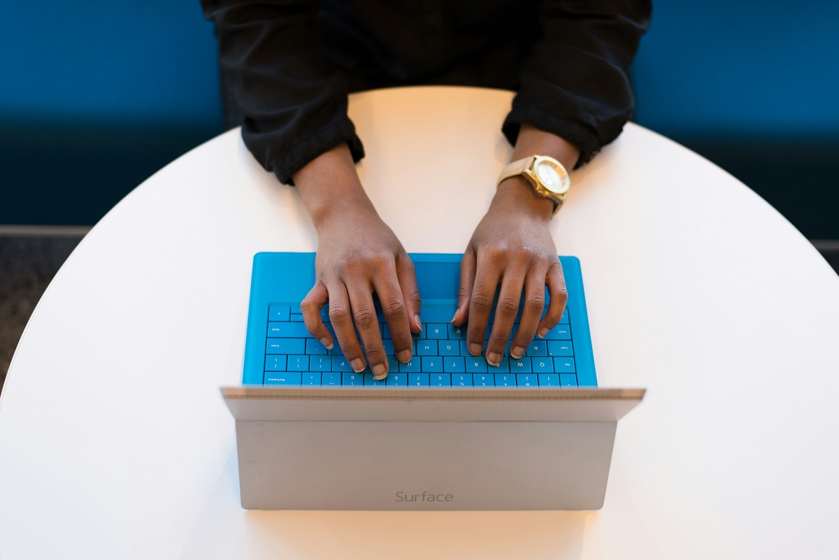 Picture of women's hands from above typing on a computer keyboard.