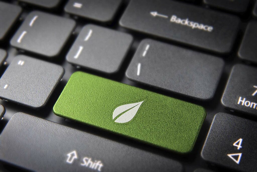 Green energy key with leaf icon on laptop keyboard.