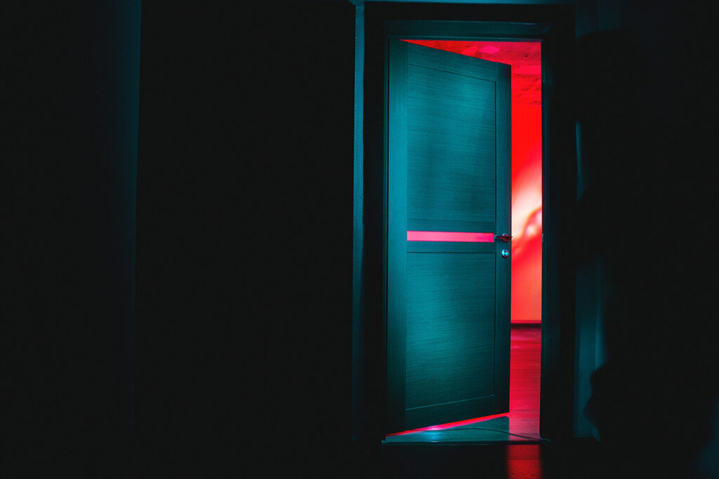 Door opening from a black room into a brightly colored room