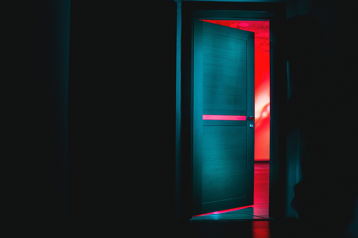 Door opening from a black room into a brightly colored room