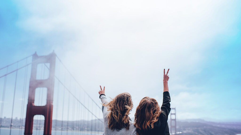 Two women making peace sign near the Golden Gate bridge, © Ian Schneider / Unsplash
