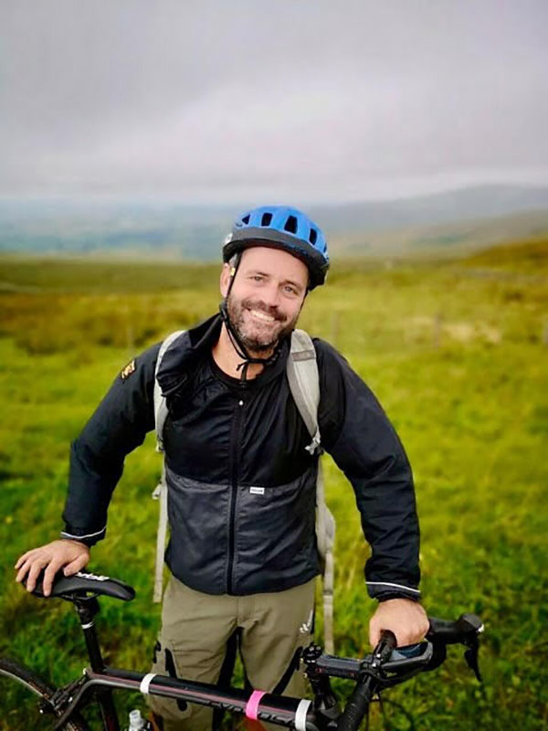 Photo of James Wight outdoors with his bicycle.