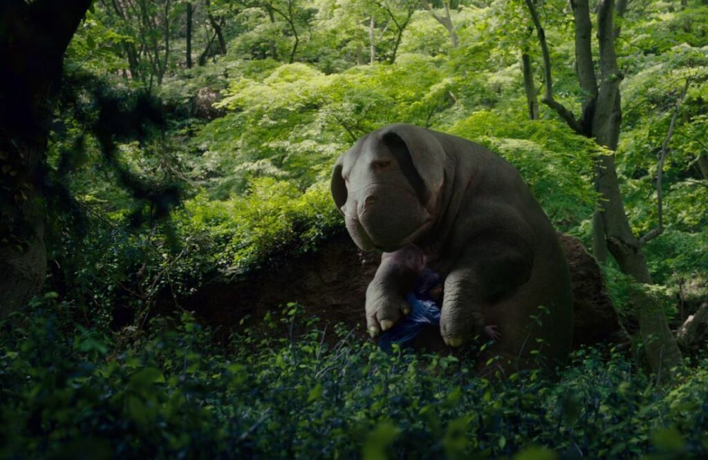 Photo from the film Okja depicting the super pig and the little girl hugging