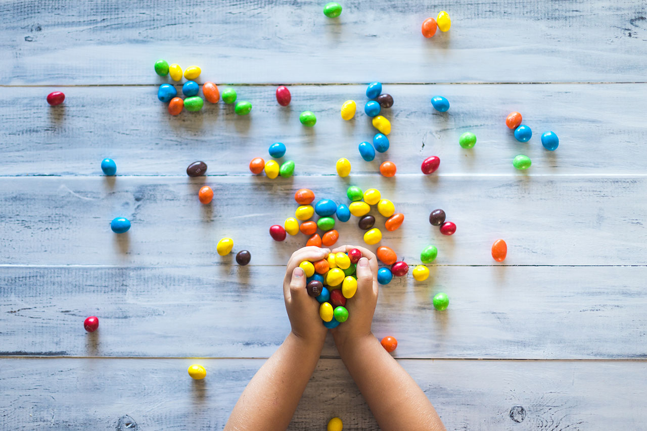 Selective photo of kid holding candies on gray wooden pallet board, © Patrick Fore / Unsplash