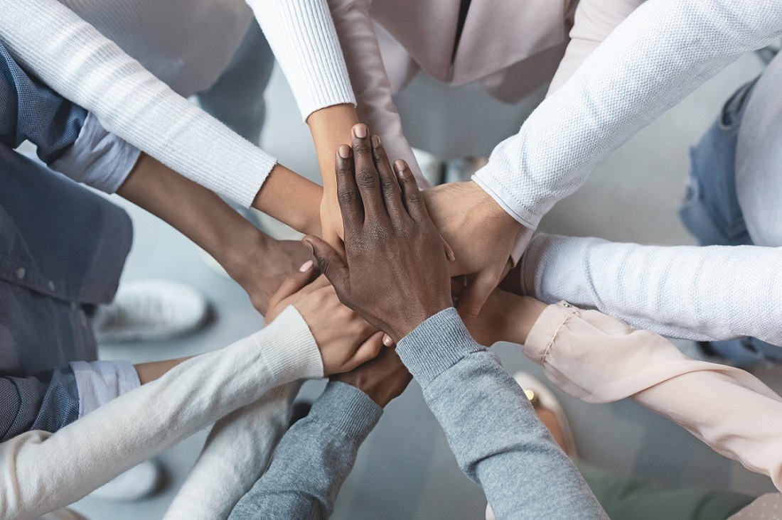 Photo of a group of diverse colleagues putting their hands together.