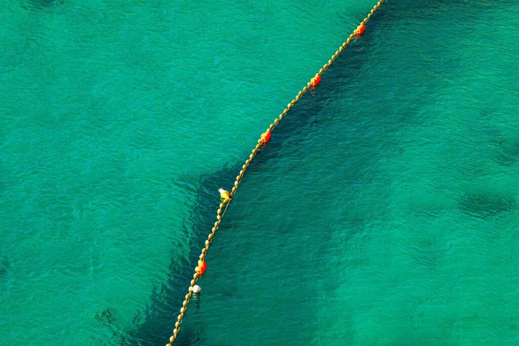 A line of bouys divides a bright green body of water