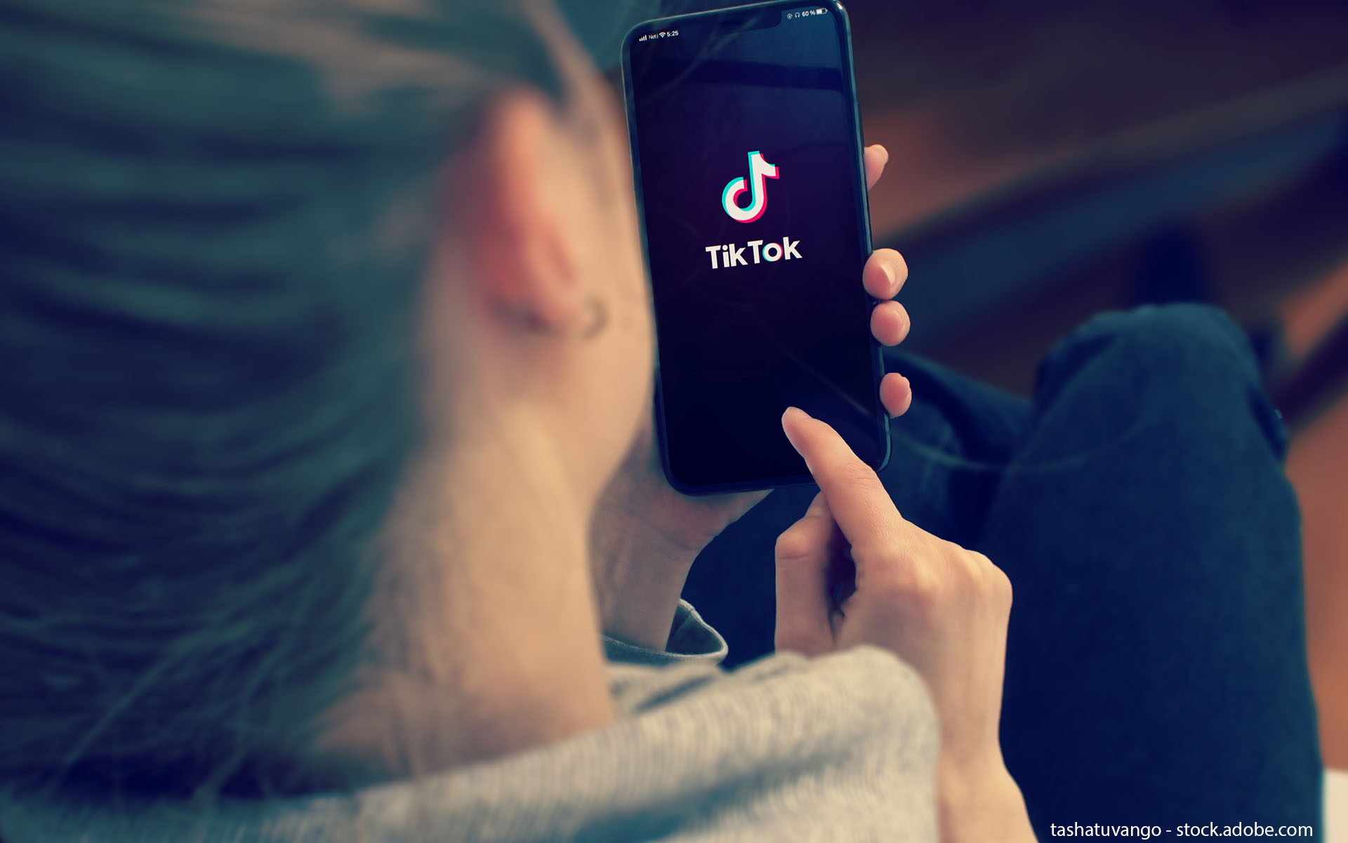 Tiktok on Smart Phone Screen. Young Girl Pointing or Texting Mobile Phone During a Pandemic Self-Isolation and Coronavirus Prevention.