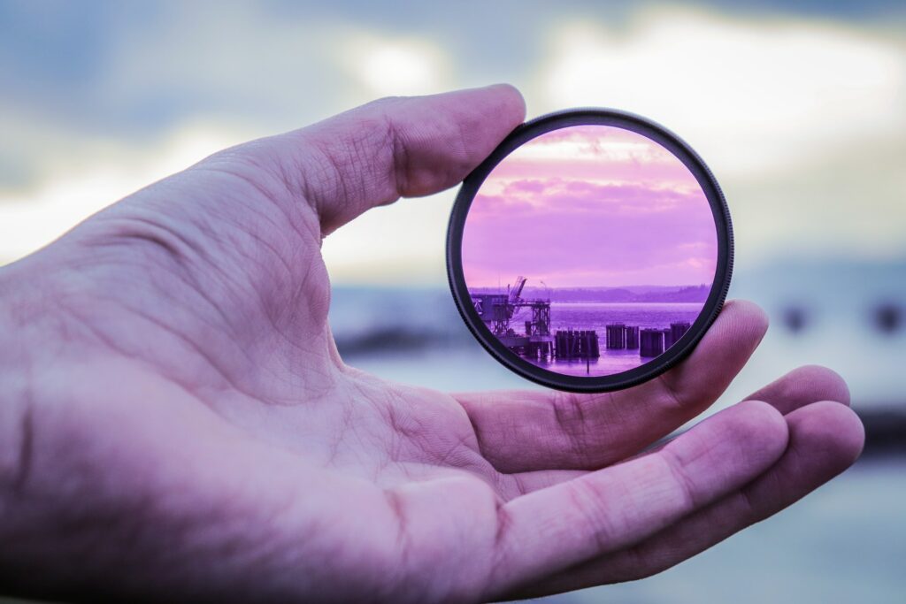 Close up photo of a hand holding a lens that is magnifying the background