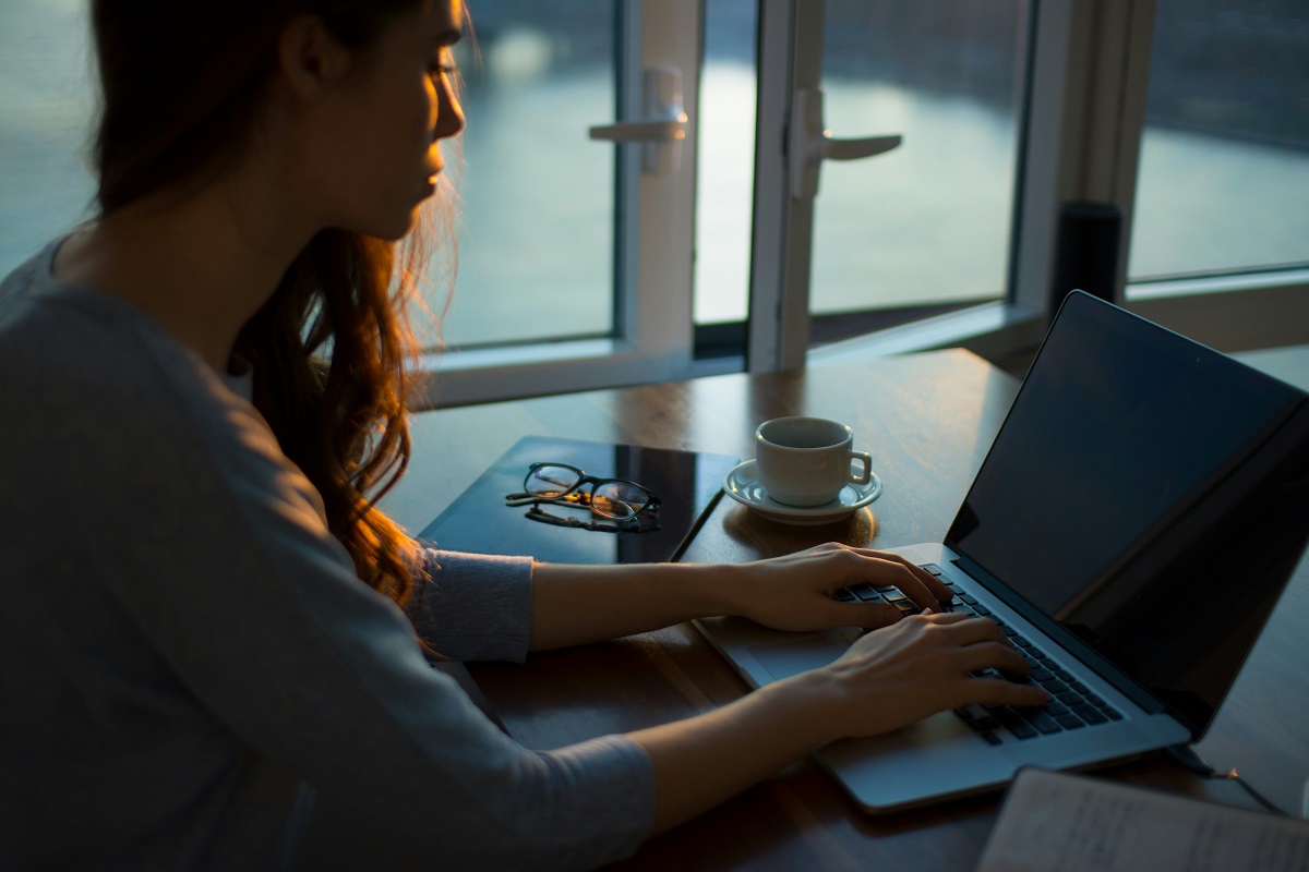 A woman sits at her desk, typing on her computer